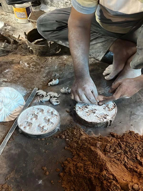 Rajasthani artisan hands detailing meenakari enamelwork on a brass box — SaarthiOnline